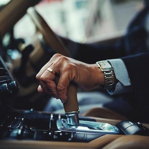 Photo of a man in a suit changing gear while driving - M&N Insurance